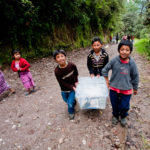 Children carry books to remote village school